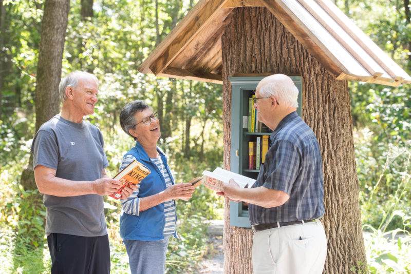 three seniors holding books and talking