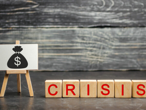 Wooden blocks with the word Crisis and the image of dollars