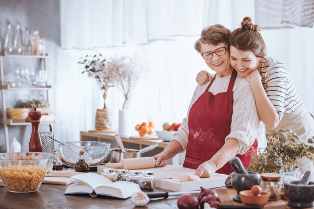 Aging mother and adult daughter baking together. 