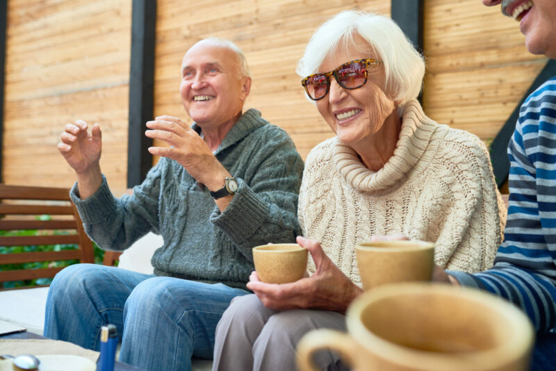 Cheerful senior friends gathered together at cozy small patio.